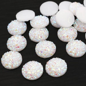 May include: Assortment of white iridescent round cabochons with a textured surface. The cabochons are approximately 1 inch in diameter.