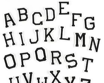 May include: Black felt letters of the alphabet, A through Z, with white outlines. The letters are arranged in three rows.