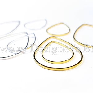 May include: A set of teardrop-shaped earring hoops in gold and silver. The hoops are made of metal and are available in two sizes.
