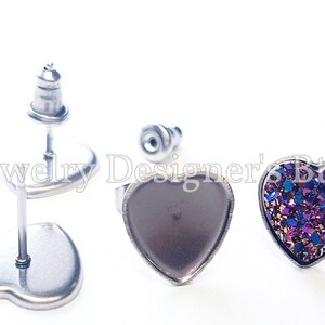 May include: A pair of heart-shaped stud earrings with a silver post and back. One earring has a purple and gold glitter heart, and the other earring has a silver heart.