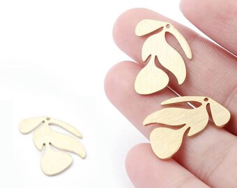 May include: Close-up of three gold-colored leaf-shaped charms. Each charm has a hole at the top for stringing. The leaves have a brushed metal finish and are arranged in a cluster of three.