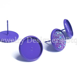 May include: Three purple metal earring settings, two are flat and one has a sparkly iridescent purple cabochon glued to the top.