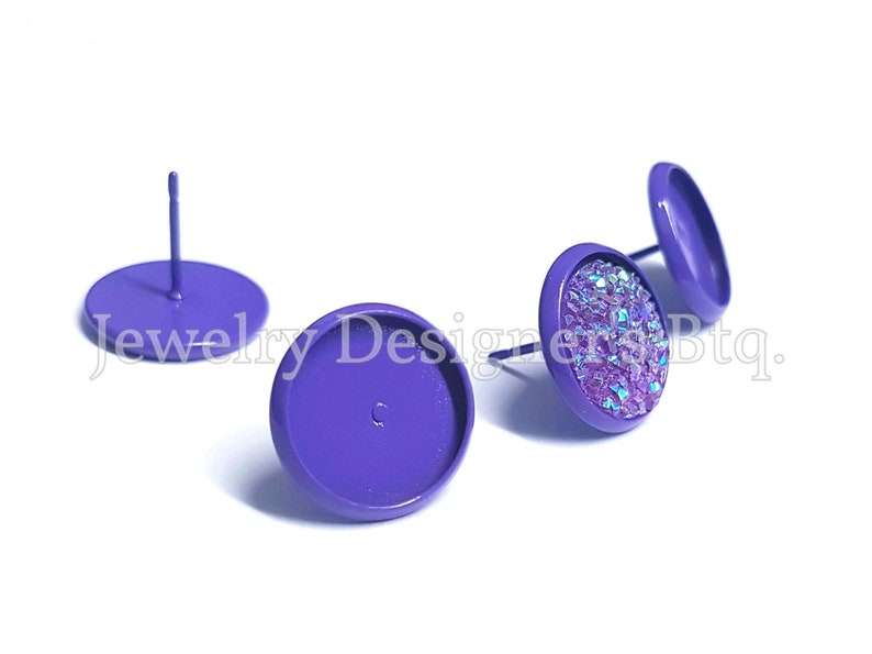 May include: Three purple metal earring settings, two are flat and one has a sparkly iridescent purple cabochon glued to the top.