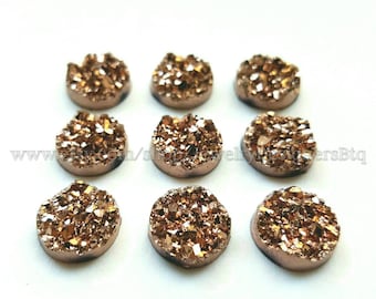 Può includere: Dieci cabochon rotondi, piatti, dorati e scintillanti in agata. I cabochon hanno un diametro di circa 2,5 cm.
