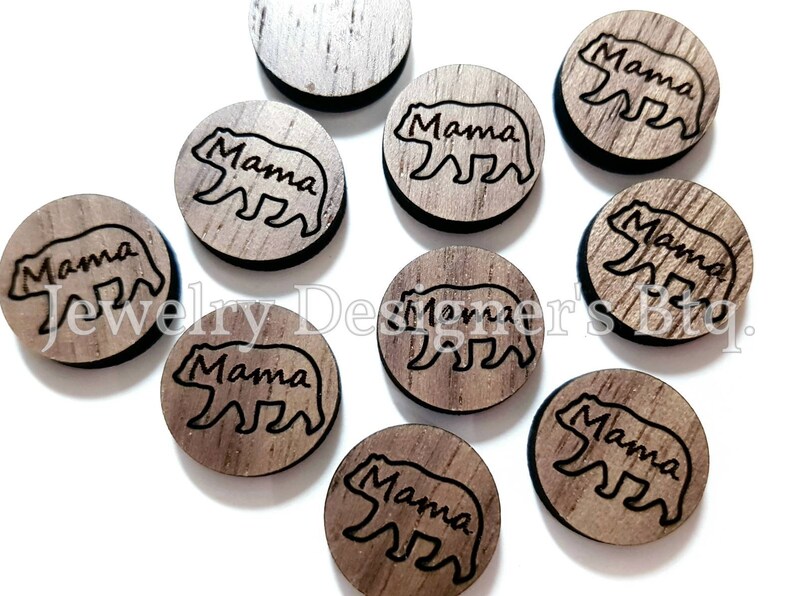 May include: Ten round wooden ornaments with a brown wood grain finish. Each ornament features a black silhouette of a bear with the word "Mama" written above it.