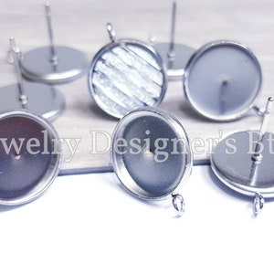 May include: A set of silver earring blanks with a round, flat base and a post for attaching earrings. The blanks are designed for crafting and customizing earrings.