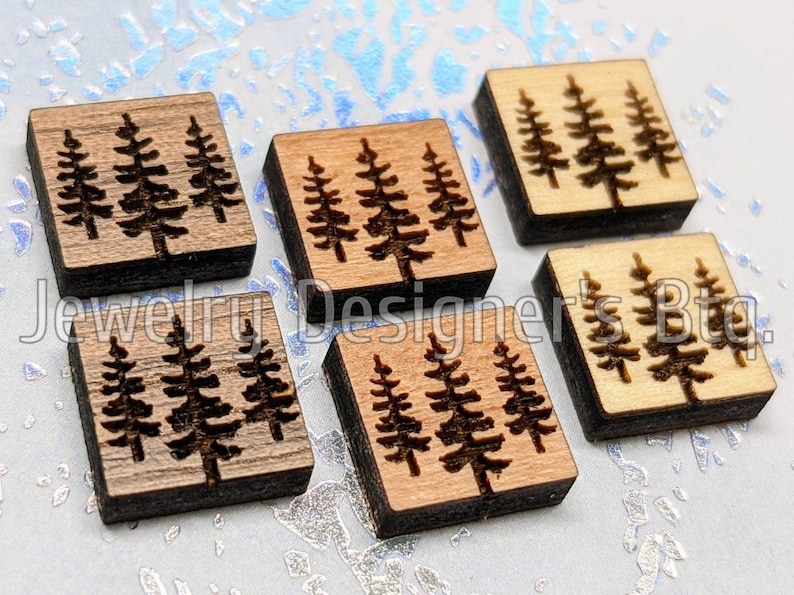Puede incluir: Seis cuadrados de madera con un dise&ntilde;o de tres pinos cortado con l&aacute;ser en cada uno. Los cuadrados son de varios tonos de marr&oacute;n y madera natural.