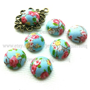 Op de afbeelding: Assortiment van zes blauwe, met stof beklede knoppen met een bloemenpatroon. De knoppen zijn ongeveer 2,5 cm in diameter.