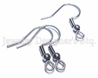 Könnte beinhalten: Drei silberfarbene Ohrhaken aus Metall mit einer Spiralfeder und einer kleinen Perle über einer geschlossenen Öse zur Befestigung. Der Text Jewelry Designer's Btq. ist in der Mitte des Bildes über den Metallkomponenten zu sehen.