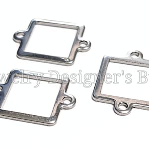 May include: Three silver-toned square jewelry findings with rounded corners and two small holes on each side. The findings are on a white background. The text "Jewelry Designer's Btd." is partially visible.