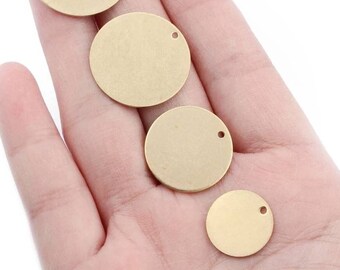 May include: Four gold-colored metal discs with a hole in the center. The discs are different sizes and are arranged in a row on a hand.