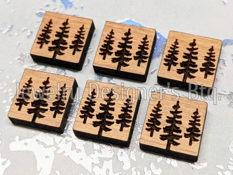 Puede incluir: Seis cuadrados de madera con un dise&ntilde;o de tres pinos cortado con l&aacute;ser. Los cuadrados son de color marr&oacute;n claro con un borde marr&oacute;n oscuro.