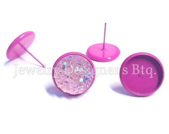 May include: Three pink metal earring bases, one with a clear iridescent glitter fill. The bases are round and have a post on the back.