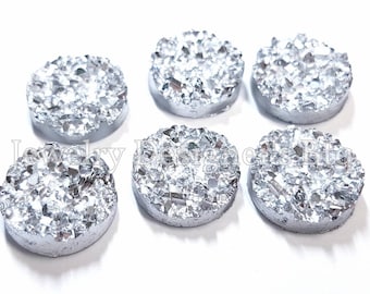 Puede incluir: Seis rodajas redondas de ágata de color plateado con una superficie rugosa y texturizada. Las rodajas tienen un diámetro aproximado de 2,5 cm.