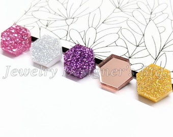May include: Five hexagon-shaped resin cabochons with glitter. The cabochons are pink, silver, purple, rose gold, and gold.