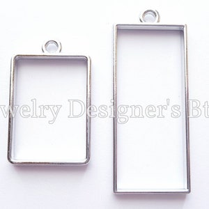 May include: Two silver metal rectangular picture frames with a loop at the top for hanging. The frames are different sizes.