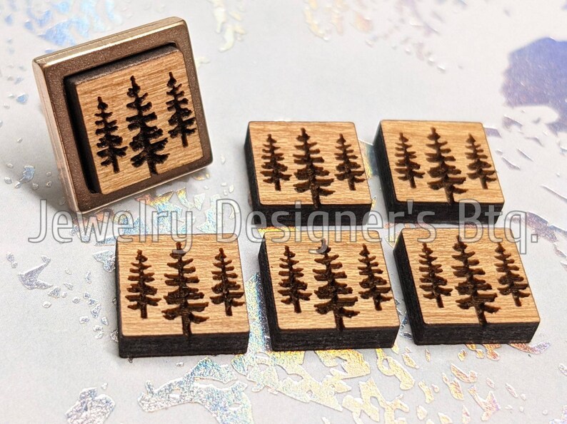 Puede incluir: Seis cuadrados de madera con un dise&ntilde;o de tres pinos grabado con l&aacute;ser en cada uno. Los cuadrados miden aproximadamente 2,5 cm por 2,5 cm.