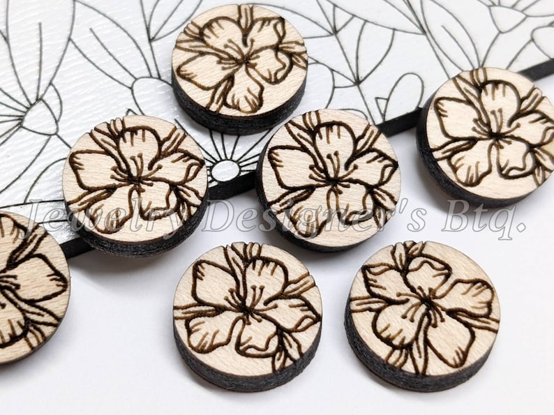 May include: Six round wooden embellishments with a laser-etched floral design. The embellishments are light brown with a dark brown outline.