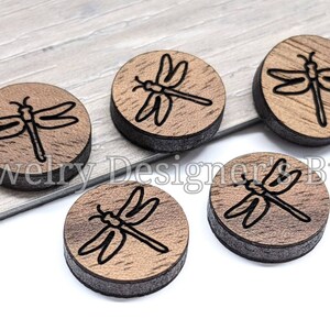 May include: Five round wooden discs with a black dragonfly design. The discs are approximately 1 inch in diameter.