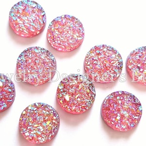 Può includere: Dieci cabochon rotondi in agata rosa e blu iridescente. I cabochon hanno un diametro di circa 2,5 cm e una superficie ruvida e testurizzata.