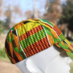 May include: A yellow, green, red, and black patterned baseball cap with a curved brim. The cap is made of fabric and has a geometric design.