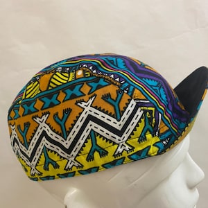May include: A colorful patterned baseball cap with a black brim. The pattern features yellow, orange, blue, green, white, and purple geometric shapes.