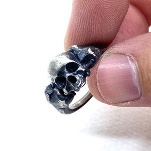 May include: A silver skull ring with a detailed design. The skull is facing forward with its mouth open.