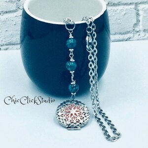 May include: A silver chain necklace with a round, openwork locket and three green beads. The locket has a peach-coloured interior.