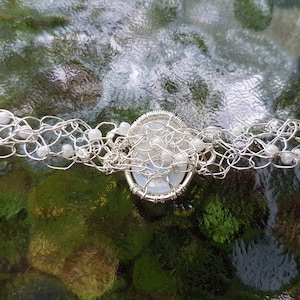 May include: A silver wire wrapped necklace with white beads and a white stone pendant.