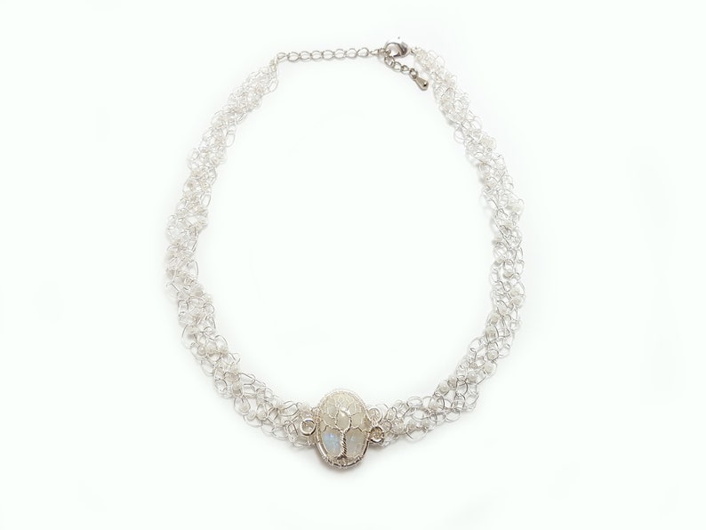 May include: A silver necklace with a delicate chain and a large oval pendant featuring a moonstone.
