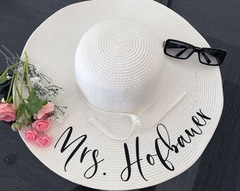 May include: White sun hat with a black ribbon and the text "Mrs. Hofbauer" written in cursive.