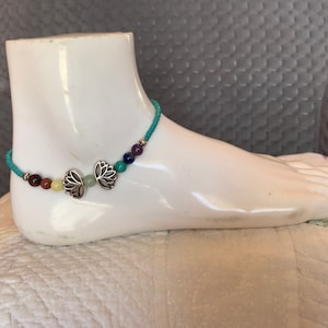 May include: A turquoise beaded anklet with silver lotus flower charms and colorful gemstone beads.