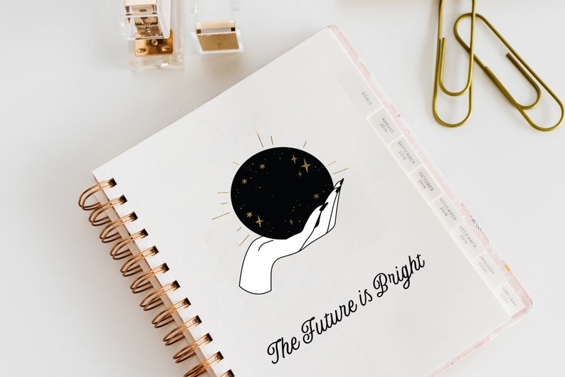 May include: A white spiral bound notebook with a black and gold illustration of a hand holding a crystal ball with stars. The text "The Future is Bright" is written in black cursive below the illustration.
