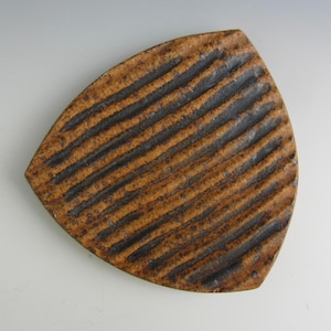 May include: A brown and black ceramic plate with a ridged surface. The plate is shaped like a triangle with rounded edges.