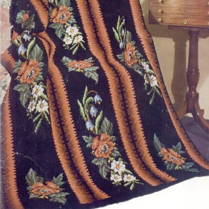 May include: A black and brown striped throw blanket with a floral pattern featuring red poppies, white flowers, and blue bells. The blanket is folded and draped over a chair.