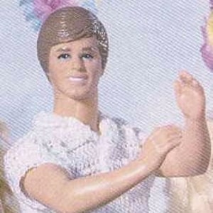 May include: A crocheted outfit for a doll, featuring a white short-sleeved shirt and black pants.