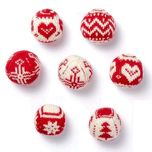 Könnte beinhalten: Sieben rot-weiß gestrickte Kugeln mit verschiedenen Mustern, darunter Herzen, Zickzack und ein Weihnachtsbaum-Design. Die Kugeln sind auf weißem Hintergrund angeordnet und präsentieren die festliche Weihnachtsdekoration.