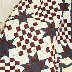 Può includere: Una coperta all'uncinetto con un motivo a scacchi in marrone e bianco, e un motivo a stella in blu navy e marrone.