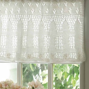 May include: White crocheted valance with a delicate pattern. The valance is made of a lightweight, airy fabric and has a ruffled edge. It is perfect for adding a touch of elegance to any window.