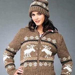 Puede incluir: Un cárdigan de punto marrón con cierre de cremallera y un estampado de renos blancos. El cárdigan tiene un pompón blanco en la capucha.
