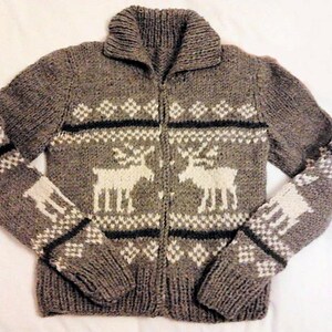 May include: A gray knitted cardigan with a white reindeer pattern. The cardigan has a zipper closure and a collar.