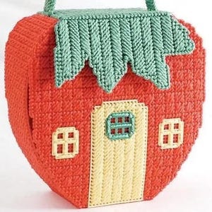 May include: A red and yellow plastic craft project shaped like a strawberry with a green leaf on top. The strawberry has a yellow door and two windows.