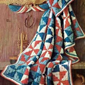 Op de afbeelding: Een gehaakt deken in een rood, wit en blauw kleurenschema. Het deken is gemaakt van vierkanten met een molenwiekenontwerp.