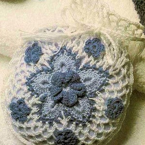 May include: A white crocheted bag with blue crocheted flowers. The bag is made with a delicate, lacy pattern.