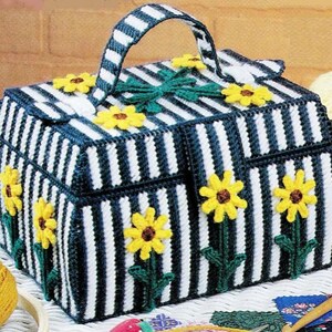 Pode incluir: Uma caixa de armazenamento de lona plástica listrada em branco e azul com alça e enfeites florais. A caixa tem vários compartimentos e é perfeita para organizar pequenos itens.