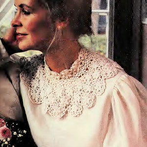 May include: A white crocheted collar with a scalloped edge. The collar is worn over a white blouse.