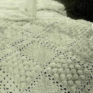 Pode incluir: Um close-up de um crochê branco com um padrão delicado e intrincado. O crochê é feito com fio fino e tem uma textura macia e arejada.