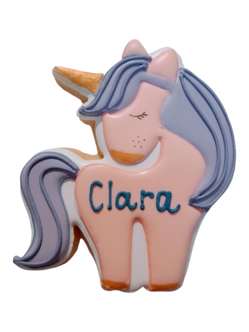 Pode incluir: Decora&ccedil;&atilde;o em forma de unic&oacute;rnio em cores pastel. O unic&oacute;rnio tem um corpo rosa, uma crina azul e um chifre dourado. O nome "Clara" est&aacute; escrito em azul no corpo.