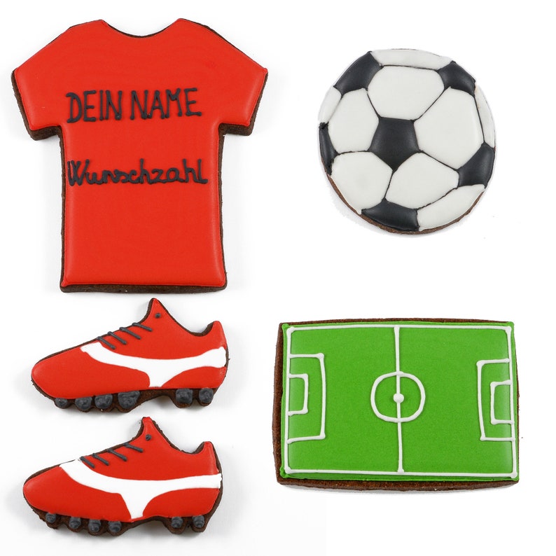 May include: A collection of decorated cookies in the shape of soccer-themed items. Includes a red jersey with the text "DEIN NAME Wunschzahl", a soccer ball, two red cleats with white accents, and a green field.
