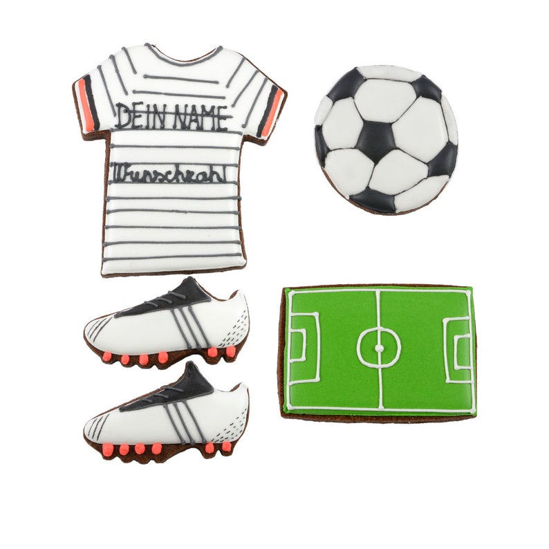 May include: A collection of decorated sugar cookies in the shape of soccer-themed items. Includes a soccer jersey with text, a soccer ball, a pair of cleats, and a soccer field. The cookies are white, black, green, and brown.